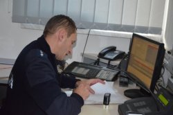zdjęcie kolorowe: oficer dyżurny podczas rozmowy telefonicznej