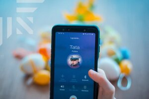 zdjęcie kolorowe: telefon komórkowy na tle świątecznego wielkanocnego stroika ze zdjęciem policjanta