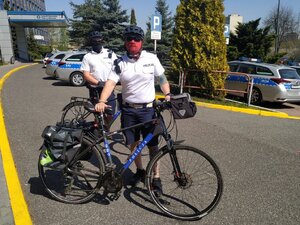 zdjęcie kolorowe: policjanci w patrolu rowerowym przed budynkiem katowickiej komendy