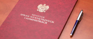 zdjęcie kolorowe: czerwona teczka ze złotym napisem Minister Spraw Wewnętrznych i Administracji