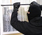 zdjęcie kolorowe: zamaskowany kominiarką mężczyzna z łomem usiłuje otworzyć okno