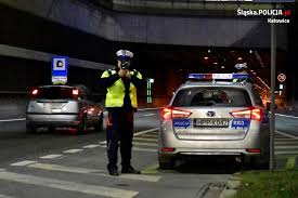 zdjęcie kolorowe: policjant katowickiej drogówki podczas pomiaru prędkości pojazdu