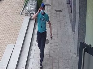 Na kolorowym zdjęciu widać wizerunek podejrzewanego o oszustwo mężczyzny który idzie chodnikiem