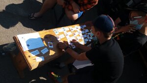 Na zdjęciu widać dwóch stolik na którym poukładane są karteczki z namalowanymi znakami informacyjnymi odnośnie bezpieczeństwa nad wodą, obok stoi chłopiec który je ogląda