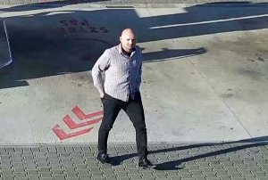 Na kolorowym zdjęciu widać łysego mężczyznę ubranego w białą koszulę i czarne spodnie jest on podejrzaną osobą o dokonanie kradzieży samochodu