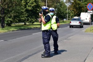 Na zdjęciu widać policjantów ruchu drogowego stojących na ulicy i mierzących prędkość