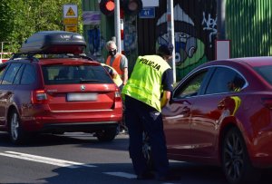 kolorowe zdjęcie: policjant stoi obok samochodu z tyłu za samochodem stoi pracownik PKP