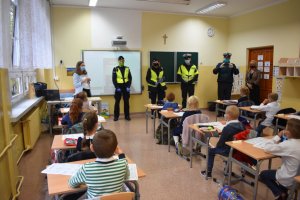 zdjęcie kolorowe: policjanci katowickiej komendy, funkcjonariusze ITD i straży miejskiej podczas spotkania z uczniami w klasie