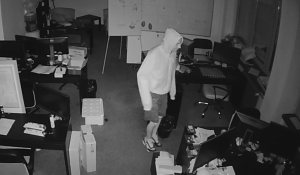zdjęcie czarno - białe: scereen z monitoringu, który zarejestrował wizerunek mężczyzny podejrzanego o kradzież laptopów, zasilaczy i gotówki z jednej z katowickich firm
