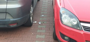 zdjęcie kolorowe: narkotyki porzucone na kostce brukowej pomiędzy dwoma samochodami