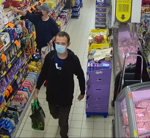zdjęcie kolorowe: dwóch mężczyzn w maseczkach na twarzy w markecie podejrzewanych o kradzież alkoholu
