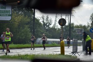 zdjęcie kolorowe: policjant oddziału prewencji nadzorujący bezpieczeństwo i zawodnicy na trasie XII Silesia Marathon biorący udział w biegu maratońskim