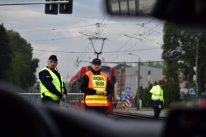 zdjęcie kolorowe: policjant i osoba nadzorująca ruchem na trasie XII Silesia Marathon strzegący bezpieczeństwa osób biorących udział w biegu maratońskim