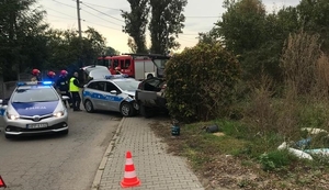 zdjęcie kolorowe: policjanci i strażacy na miejscu zdarzenia drogowego, w którym bral udział policyjny radiowóz i alfa romeo kierowana przez nietrzeźwego kierujacego