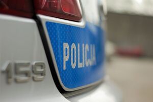 zdjęcie kolorowe: tył policyjnego radiowozu z napisem Policja