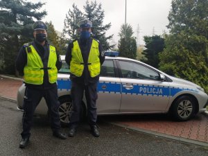 zdjęcie kolorowe: mł. asp. Krystian Mroziński i  sierż. sztab. Sebastian Bombik policjanci katowickiej drogówki przed radiowozem