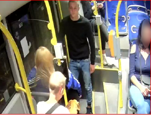 Zdjęcie przedstawia mężczyznę w czarnej bluzie i jasnych spodniach, który znajduje się w autobusie miejskim.