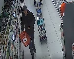 Zdjęcie kolorowe, na którym widać mężczyznę ubranego w czarną czapkę z daszkiem, ciemną kurtkę i jeansy w pomieszczeniu.