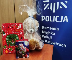 Zdjęcie kolorowe, na którym widać prezenty świąteczne oraz napis &quot;POLICJA Komenda Miejska Policji w Katowicach&quot;.