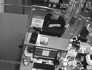 zdjęcie czarno-białe: mężczyzna w ciemnej bluzie dresowej i maseczce ochronnej na twarzy przy ladzie aptecznej