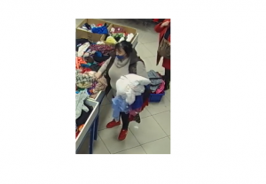 zdjęcie kolorowe: otyła kobieta podejrzewana o kradzież torebki, ubrana w szary długi sweter z golfem, ciemna kamizelkę, ciemne spodnie i czerwone sportowe buty