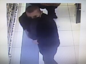 zdjęcie kolorowe: mężczyzna z krótko obciętymi włosami na tzw. jeża ubrany w ciemne spodnie, ciemna kurtkę i czarna maseczkę ochronna na twarzy