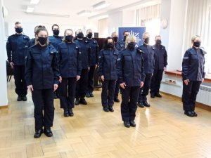 zdjęcie kolorowe: 14 nowych policjantów stojących w sali odpraw