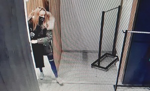 zdjęcie kolorowe: młoda kobieta o blond włosach z maseczka ochronna na twarzy wychodząca z przebieralni z czarną kurtką