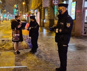 zdjęcie kolorowe: na pierwszym planie umundurowany policjant, a w tle policjantka rozmawiająca z przechodniami
