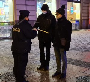 zdjęcie kolorowe: policjantka rozmawiając na chodniku z dwoma mężczyznami