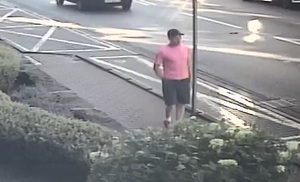 zdjęcie kolorowe: mężczyzna w różowej koszulce z krótkim rękawem i niebieskich krótkich spodenkach idący chodnikiem