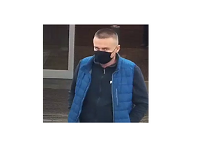 zdjęcie kolorowe: mężczyzna obcięty na jeża w niebieskiej materiałowej maseczce na twarzy, granatowej bluzie z dresu i puchowej niebieskiej kamizelce