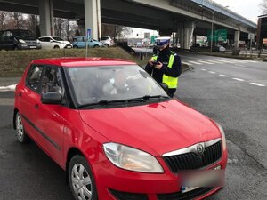 zdjęcie kolorowe: policjant katowickiej drogówki podczas kontroli drogowej rozmawiający z kierującym który dopuścił się wykroczenia