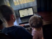 zdjęcie kolorowe: dwoje małych chłopców stojących przed włączonym laptopem