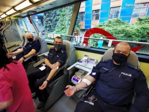 zdjęcie kolorowe: trzech policjantów siedzących w ambulansie krwiodawstwa oddających honorowo krew