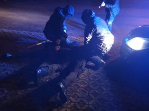 zdjęcie kolorowe: policjanci katowickiej komendy z zatrzymanym mężczyzną leżącym na ziemi