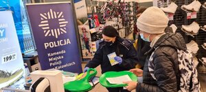 zdjęcie kolorowe: policjantka katowickiej komendy podczas akcji profilaktycznej w sklepie sportowym rozmawia z kobietą