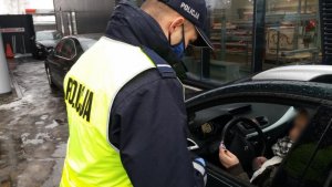 zdjęcie kolorowe: policjant rozmawiający o bezpieczeństwie w ruchu drogowym z kierującą samochodem osobowym