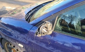 zdjęcie kolorowe: niebieski samochód osobowy z uszkodzonym lewem lusterkiem bocznym
