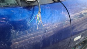 zdjęcie kolorowe: uszkodzony niebieski samochód osobowy z urwanym lusterkiem bocznym