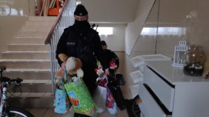zdjęcie kolorowe: katowiccy policjanci wnoszący torby z zabawkami do placówki opiekuńczej