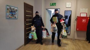 zdjęcie kolorowe: policjant i policjantka w przedpokoju domu dziecka z prezentami