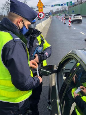 zdjęcie kolorowe: policjant katowickiej drogówki i po9licjant prewencji rozmawiający z kierującym podczas kontroli