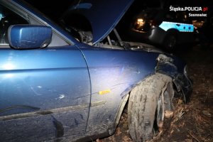 zdjęcie kolorowe: uszkodzone BMW i policyjny radiowóz w tle