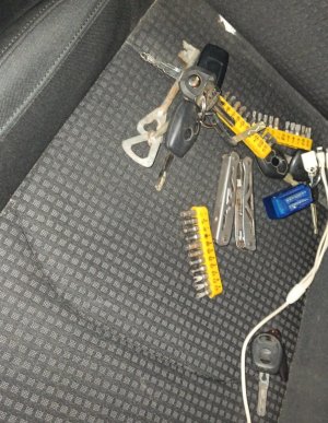 zdjęcie kolorowe: bezpieczniki i klucze samochodowe leżące na tylnej kanapie samochodu KIA