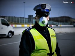 zdjęcie kolorowe: policjant ruchu drogowego w maseczce ochronnej zasłaniającej usta i nos