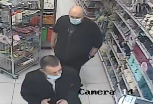 zdjęcie kolorowe: dwóch mężczyzn podejrzewanych o kradzież w drogerii I z mężczyzn jest otyły, ubrany w czarny sweter rozpinany na zamek i czarna koszule, łysy z maseczka ochronna na twarzy, II z mężczyzn szczupły, ubrany w czarny sweter rozpinany na zamek i biała koszulkę z krótko obciętymi ciemnymi włosami