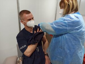 zdjęcie kolorowe: policjant katowickiego garnizonu podczas iniekcji szczepionki