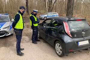 zdjęcie kolorowe: policjanci katowickiej komendy podczas kontroli drogowej samochodu osobowego, w tle dwa policyjne radiowozy