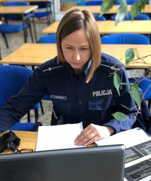 zdjęcie kolorowe: policjantka katowickiej komendy podczas zajęć on-line z uczniami klas maturalnych